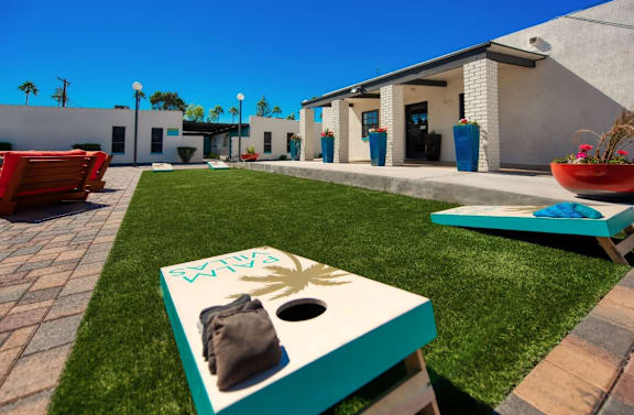 A cornhole game set up on a green lawn in front of a house at Palm Villas Apartments, Scottsdale, AZ 85257