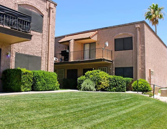 A building with a balcony and a palm tree in the background.