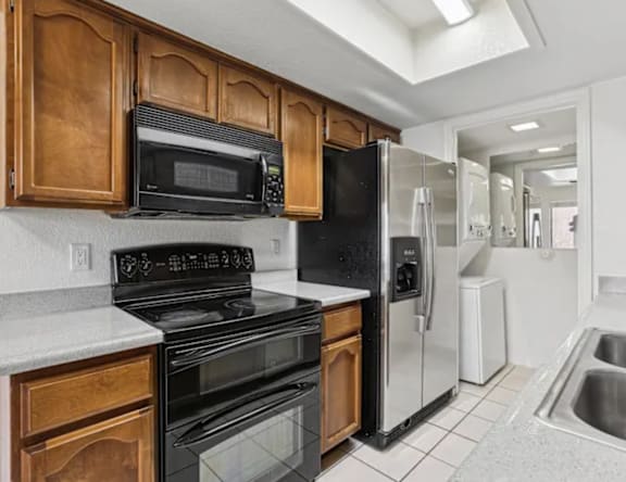 A kitchen with black appliances and wooden cabinets.