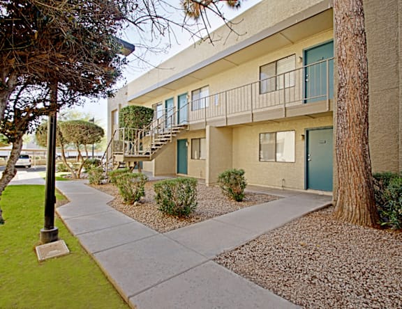 A concrete walkway leads to a building with a balcony.