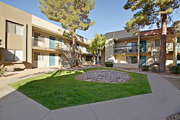 A courtyard with a grassy area and a concrete walkway in front of apartment buildings.
