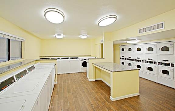 A laundry room with a washer and dryer on the left and a row of ovens on the right.