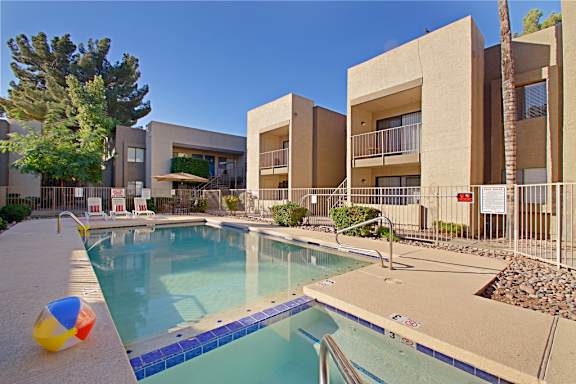 A pool with a blue tiled edge and a yellow, red and blue ball on the side.