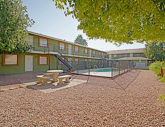 A playground area with a slide and picnic table in front of a building.
