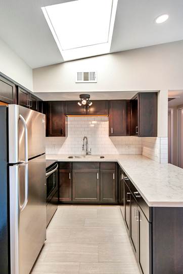 A modern kitchen with a refrigerator on the left and a sink in the middle.