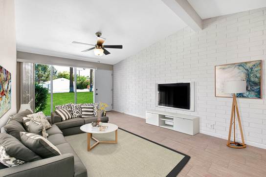 A living room with a grey couch and a white television.