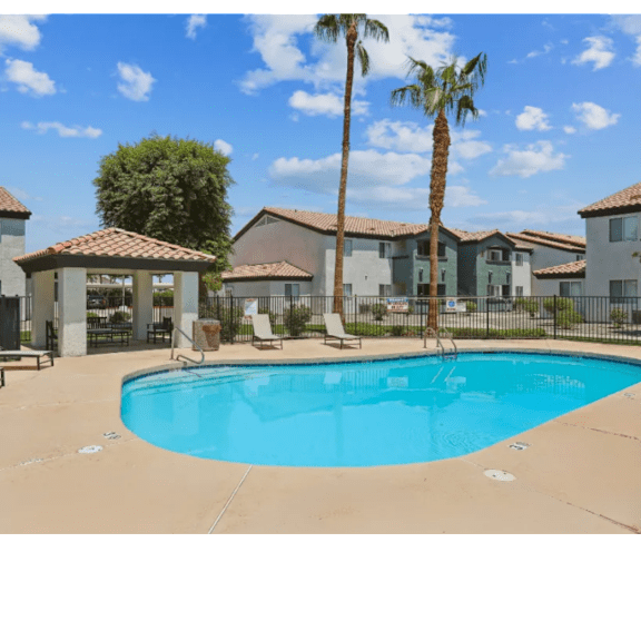 A swimming pool in front of a building with a palm tree.