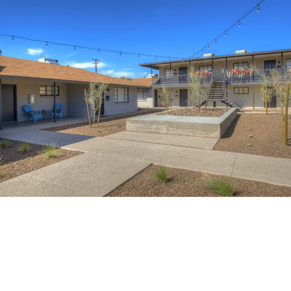 A sunny day at the outdoor patio of a building with blue chairs and a string of lights.