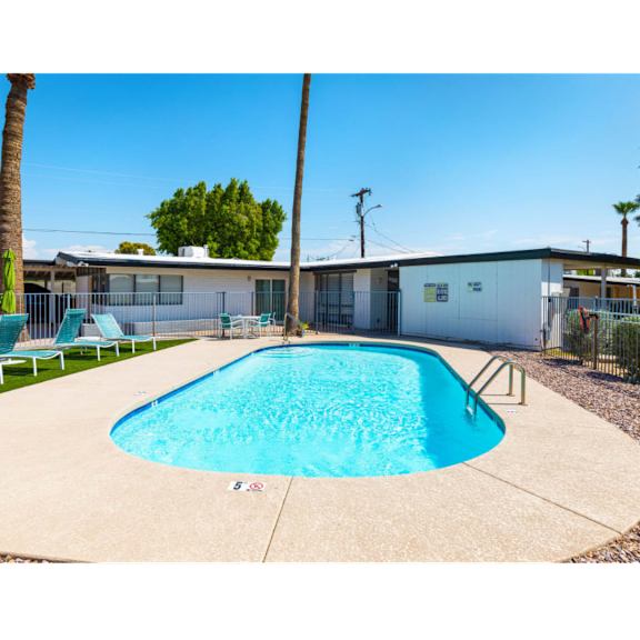 A small pool surrounded by a fence and a building in the background.