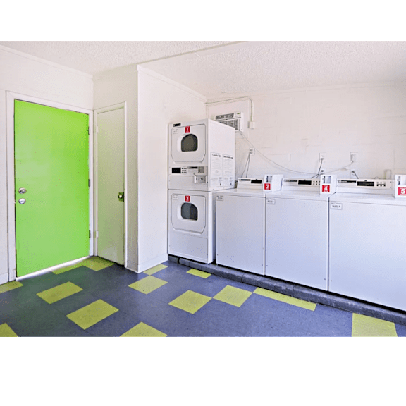 A room with a green door and a row of white cabinets.