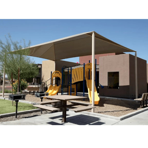 A playground with a yellow slide and a brown picnic table.