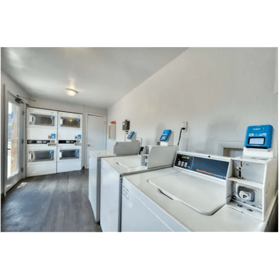 A modern kitchen with a washing machine and ovens.