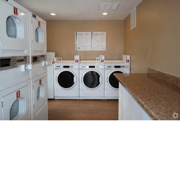 A row of white front load washing machines in a laundromat.