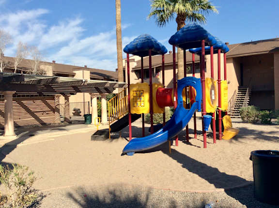 A playground with a blue slide and yellow and red slides.