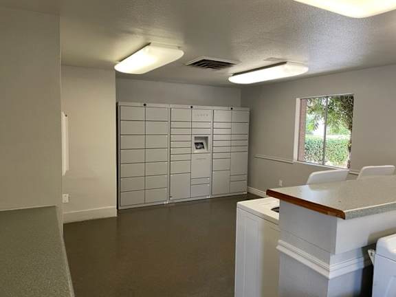 A white cabinet with a brown countertop sits in a room with a window.