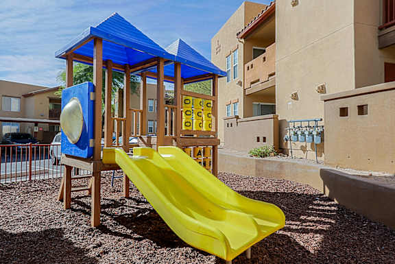 A playground with a yellow slide and a blue canopy.