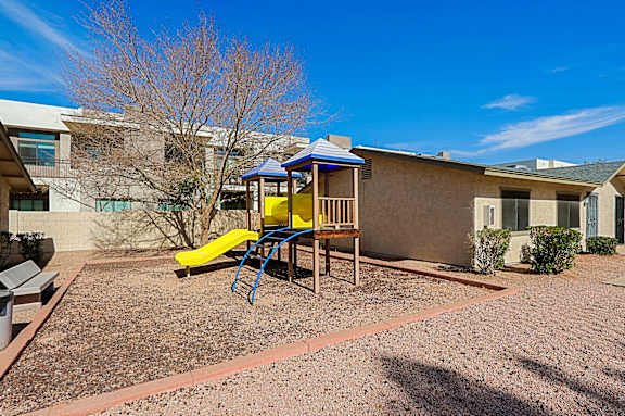 A playground with a yellow slide and a blue canopy.