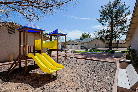 A playground with a yellow slide and a blue roofed structure.