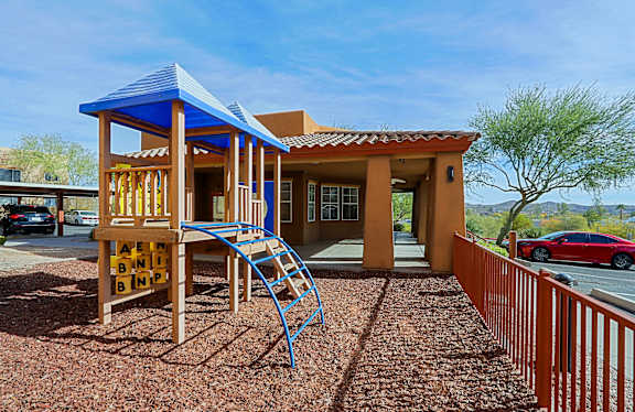 A small house with a blue roof and a wooden play structure in front.