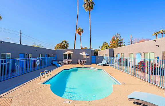 A pool surrounded by a fence with a blue sky in the background.