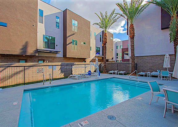 A swimming pool in front of a building with palm trees.