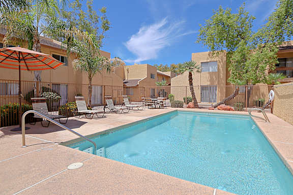 A swimming pool surrounded by chairs and umbrellas.