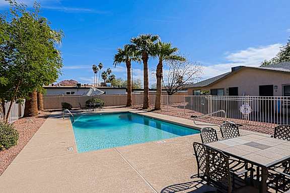 A pool surrounded by a table and chairs.