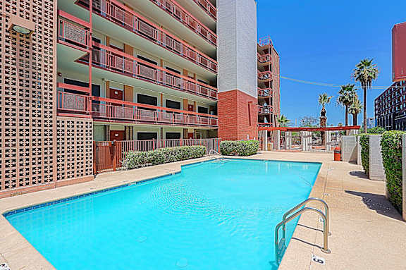 A large swimming pool is surrounded by a red brick building.