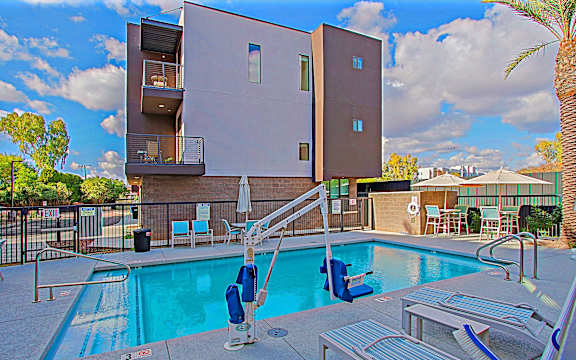 A swimming pool with a diving board and lounge chairs in front of a building.