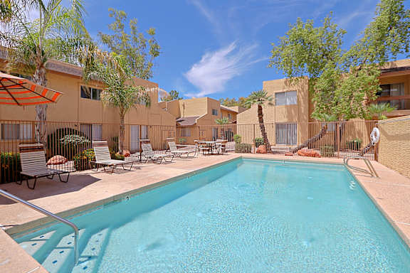 A swimming pool surrounded by lounge chairs and umbrellas.