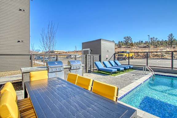 the deck has a pool and a table with chairs and a grill at 2051 Apartments, Prescott, 86301