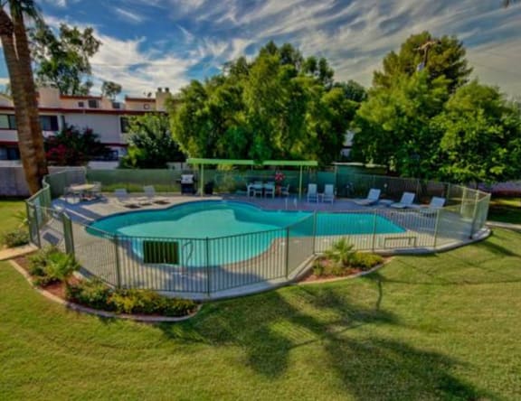 A small pool surrounded by a fence and trees.