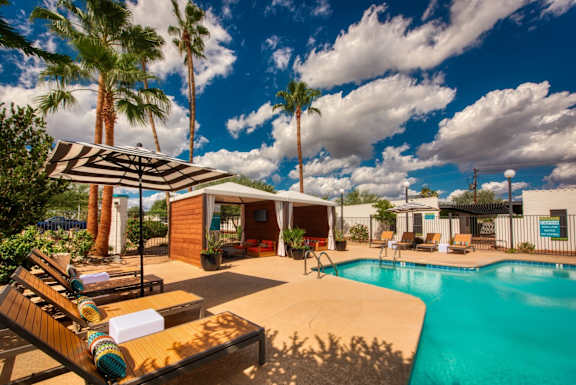 A poolside area with a sun lounger and a striped umbrella.
