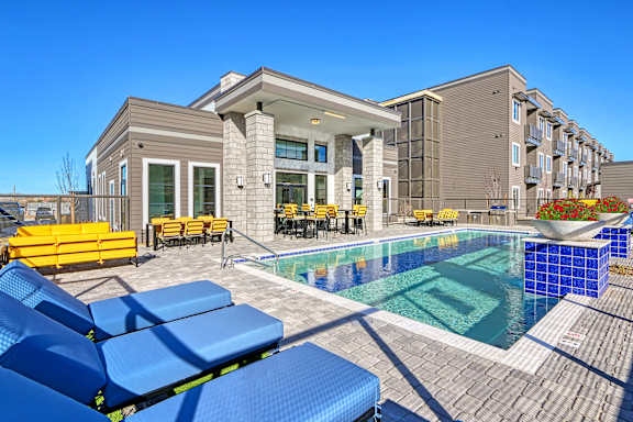 A pool surrounded by blue lounge chairs and a building in the background.