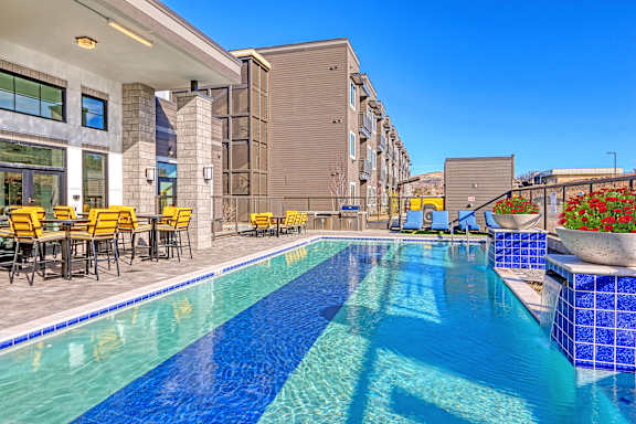 a swimming pool with tables and chairs next to a building