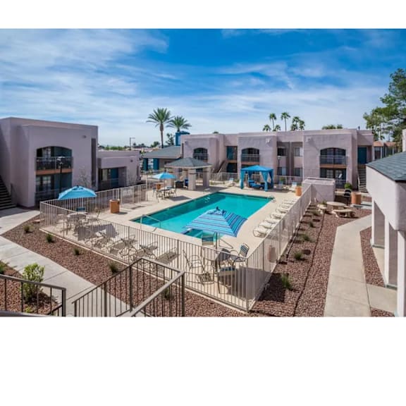 A swimming pool surrounded by a metal fence and palm trees.