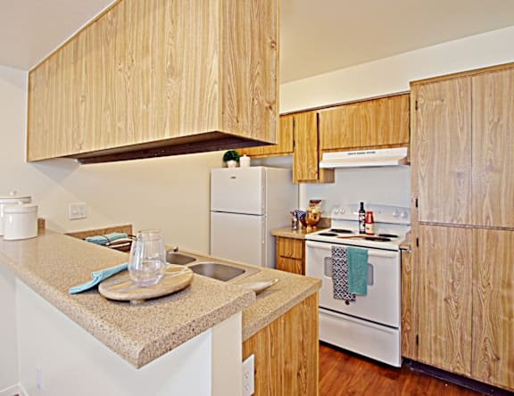 A kitchen with wooden cabinets and a white stove top oven.