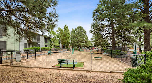 A playground with a green bench and a fence.