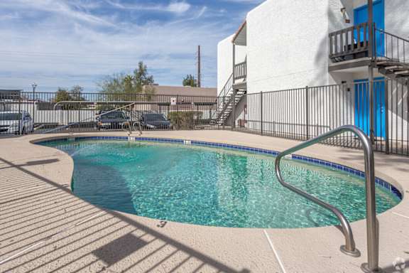 A small pool with a metal railing and steps leading to a balcony.