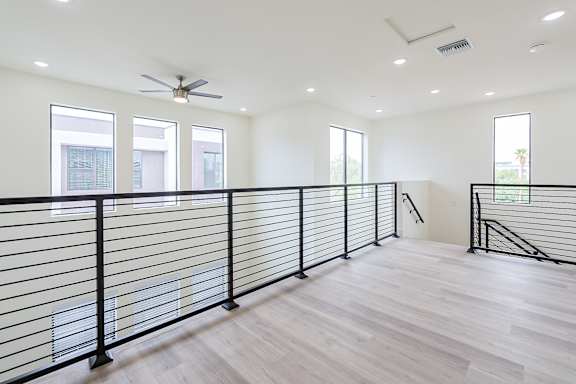 A spacious room with a black railing and wooden flooring.