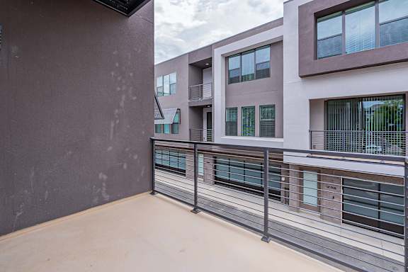 A balcony with a metal railing and a building in the background.