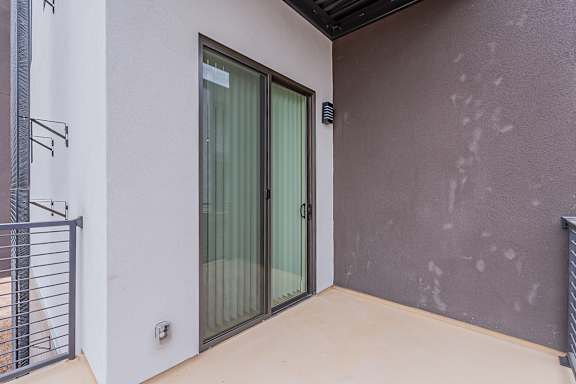 A balcony with a sliding door and a metal railing.
