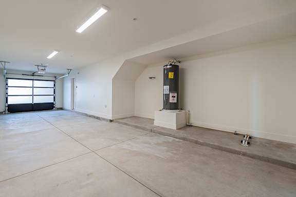 A large empty room with a white ceiling and a window on the left side.