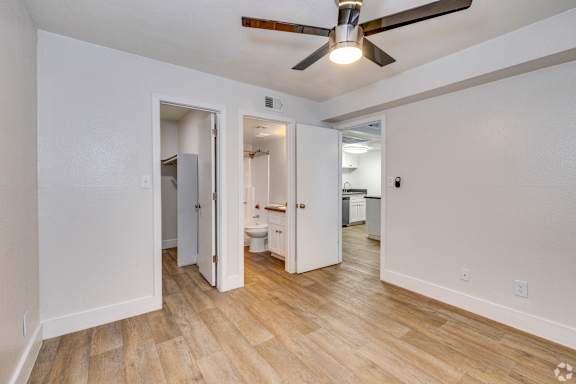 A room with a ceiling fan and wooden flooring.