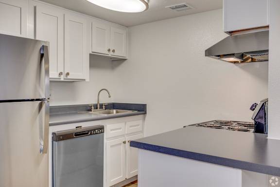 A kitchen with a refrigerator, dishwasher, and a sink.