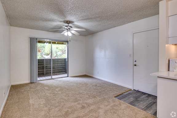 A room with a ceiling fan and a window with blinds.