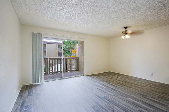 A room with a ceiling fan and sliding glass doors.