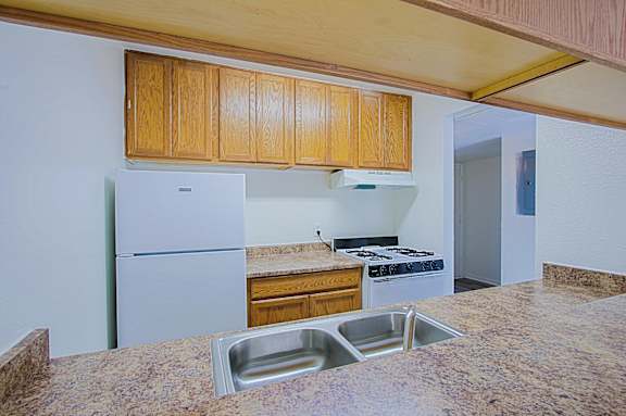 A kitchen with a granite counter top and wooden cabinets.