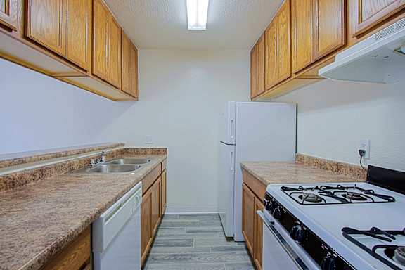 A kitchen with a white refrigerator, brown cabinets, and a white stove top.