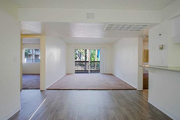 A spacious room with wooden flooring and white walls.
